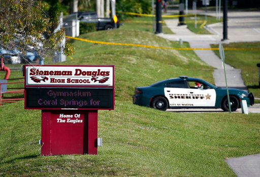 FILE - Law enforcement officers block off the entrance to Marjory Stoneman Douglas High School in Parkland, Fla., Feb. 15, 2018, the day after a deadly shooting at the school. Jurors in the trial of Florida school shooter Nikolas Cruz are expected to walk through the still blood-spattered rooms of the high school Thursday, Aug. 4, 2022, in a visit to the three-story building where he murdered 14 students and three staff members four years ago. (AP Photo/Wilfredo Lee, File)