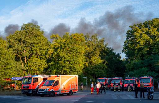 Fire engines and ambulances stand on Kronprinzessinnen road at the Grunewald forest in Berlin, Germany, Thursday, Aug. 4, 2022. A large fire has broke out in one of Berlin&rsquo;s biggest forests triggered by several explosions that took place on a blasting site inside the forest leading to canceled public transportation and the closure of several roads. Christophe Gateau/dpa via AP)