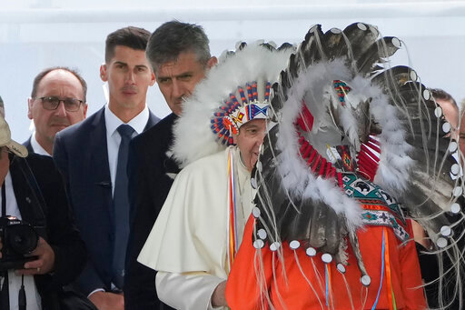 Massimiliano Strappetti, left, watches Pope Francis putting on an indigenous headdress during a meeting with indigenous communities, including First Nations, Metis and Inuit, at Our Lady of Seven Sorrows Catholic Church in Maskwacis, Canada, Monday, July 25, 2022. Francis has promoted the Vatican nurse whom he credited with saving his life to be his &quot;personal health care assistant.&quot; The Vatican announced the appointment of Massimiliano Strappetti, currently the nursing coordinator of the Vatican's health department, in a one-line statement Thursday, Aug. 4, 2022.(AP Photo/Gregorio Borgia)
