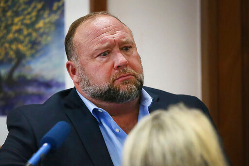 Conspiracy theorist Alex Jones attempts to answer questions about his emails asked by Mark Bankston, lawyer for Neil Heslin and Scarlett Lewis, during trial at the Travis County Courthouse in Austin, Wednesday Aug. 3, 2022. Jones testified Wednesday that he now understands it was irresponsible of him to declare the Sandy Hook Elementary School massacre a hoax and that he now believes it was &ldquo;100% real.&quot; (Briana Sanchez/Austin American-Statesman via AP, Pool)