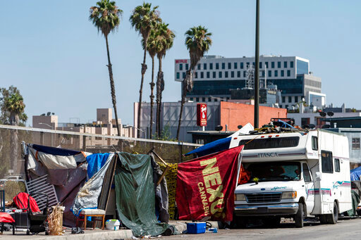FILE - Homeless encampments block the street on an overpass of the Hollywood freeway in Los Angeles, in July 7, 2021. The Los Angeles City Council has voted to ban homeless encampments within 500 feet of schools and daycare centers. The council voted Tuesday, Aug. 9, 2022 to broaden an existing ban on sleeping or camping near the facilities. (AP Photo/Damian Dovarganes, File)