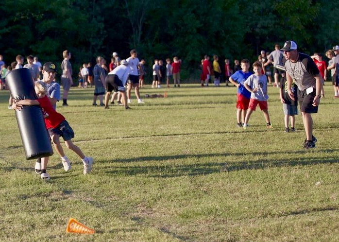 Camp Director Jason Clemensen applauds a camper for his form while taking part in a tackling drill at the Frontenac Sports Complex on Wednesday evening.