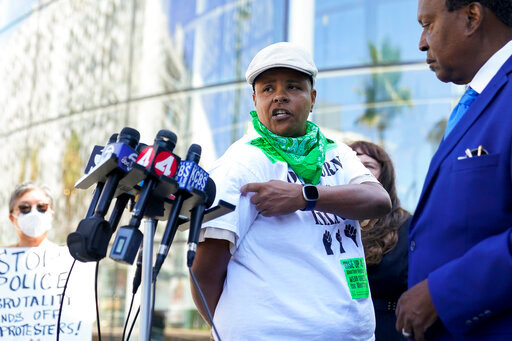 Kareim McKnight, center, talks to reporters during a press conference outside Chase Center, announcing the filing of a federal civil rights lawsuit against the San Francisco Fire and Police Departments in San Francisco, Wednesday, Aug. 10, 2022. McKnight alleges a paramedic, under the orders of a police sergeant, injected her with a sedative while she was handcuffed after protesting the Supreme Court's Roe v. Wade decision during a Golden State Warriors championship game. (AP Photo/Godofredo A. V&aacute;squez)