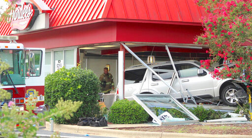 A Wilson, N.C., Fire/Rescue Services firefighter stands behind a sport utility vehicle that crashed into a Hardee&rsquo;s restaurant on Sunday, Aug. 14, 2022, in Wilson, N.C. The Wilson Police Department is investigating the wreck, from which it said two customers inside the restaurant died. (Drew C. Wilson/The Wilson Times via AP)