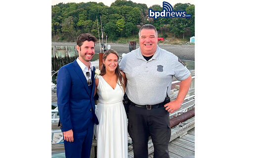 This photo provided by the Boston Police Dept., shows from left, Patrick Mahoney, Hannah (Crawford) Mahoney and Boston police officer Joe Matthews on the dock at Thompson Island  in Boston Harbor  on Saturday, Aug. 13, 2022.  Patrick Mahoney was scheduled to get married on Thompson Island, but the boat that was supposed to ferry him to the island where his bride-to-be was waiting broke down.  Officer Matthews transported the groom and his party to the island on his police boat so Mahoney&rsquo;s marriage to Hannah Crawford could go on as scheduled.(Boston Police Dept. via AP)