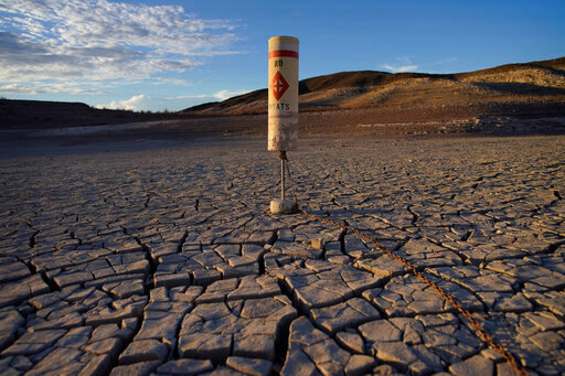 A buoy sits high and dry on cracked earth previously under the waters of Lake Mead at the Lake Mead National Recreation Area near Boulder City, Nev., on June 28, 2022. Federal officials on Tuesday, Aug. 16, 2022, are expected to announce water cuts that would further reduce how much Colorado River water some users in the seven U.S. states reliant on the river and Mexico receive. (AP Photo/John Locher)