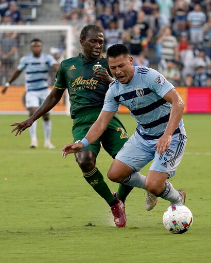 Sporting Kansas City midfielder Roger Espinoza (15) and Portland Timbers midfielder Diego Char&aacute; (21) chase the ball during the first half of an MLS soccer match Sunday, Aug. 21, 2022, in Kansas City, Kan. (AP Photo/Charlie Riedel)