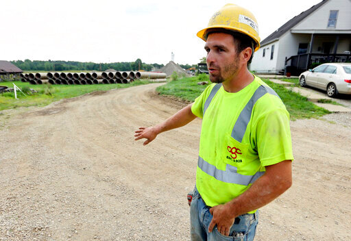 Taylor Purdy, a pipe layer with Complete General Construction, answers questions about his experience working around the new Intel semiconductor manufacturing plant construction site in Johnstown, Ohio, during an interview near the site Friday, Aug. 5, 2022. Purdy spends his days in trenches helping position storm and sanitary sewers and waterlines. Overtime is plentiful as deadlines approach. (AP Photo/Paul Vernon)