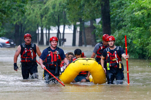 FILE - Members of the Balch Springs Fire Department bring a family of four by boat to higher ground after rescuing them from their home along Forest Glen Lane in Batch Springs, Texas, Aug. 22, 2022. This summer the weather has not only been extreme, but it has whiplashed from one extreme to another. Dallas, St. Louis, Kentucky, Yellowstone, Death Valley all lurched from drought to flood. (El&iacute;as Valverde II/The Dallas Morning News via AP, File)/The Dallas Morning News via AP)