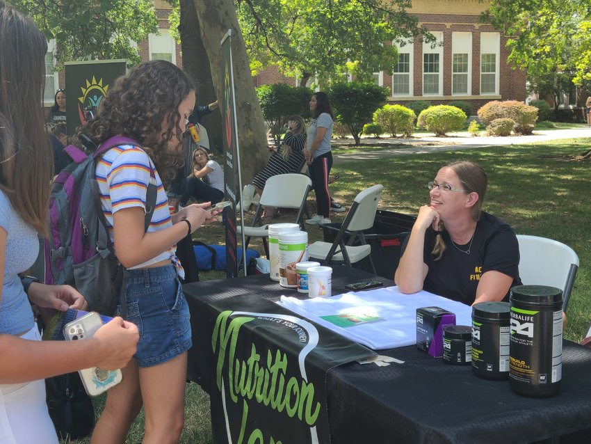 Barbie Dickinson, right, of Nutrition Lane, tells student Alison Roy about the business&rsquo; second location that will be opening soon, Jungle Nutrition, at the community fair on PSU campus on Tuesday.