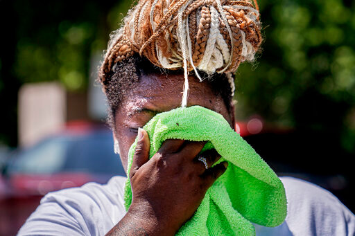 FILE - Nicole Brown wipes sweat from her face while setting up her beverage stand near the National Mall on July 22, 2022, in Washington. What's considered officially &ldquo;dangerous heat&rdquo; in coming decades will likely hit much of the world at least three times more often as climate change worsens, according to a new study. (AP Photo/Nathan Howard, File)