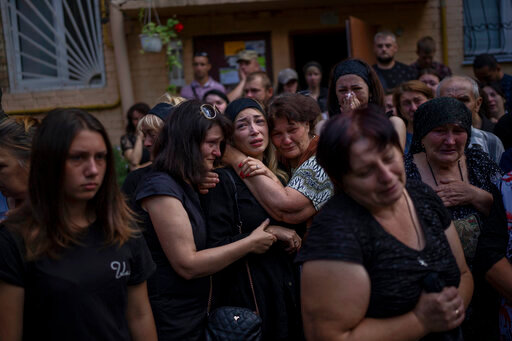 Anastasia Ohrimenko, 26, is comforted by relatives and friends as she cries next to a coffin with the body of her husband Yury Styglyuk, a Ukrainian serviceman who died in combat on August 24 in Maryinka, Donetsk, during his funeral in Bucha, Ukraine, Wednesday, Aug. 31, 2022. (AP Photo/Emilio Morenatti)