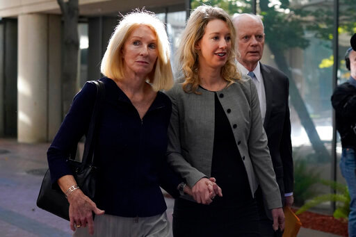 FILE - Former Theranos CEO Elizabeth Holmes, center, her mother, Noel Holmes, left, and father, Christian Holmes IV, arrive at federal court in San Jose, Calif., Thursday, Sept. 1, 2022. Elizabeth Holmes on Tuesday, Sept. 6, 2022, requested a new trial in documents asserting that a key witness who testified against her now regrets the role he played in her criminal conviction for lying to investors about the flaws in a blood-testing technology that she had hailed as a medical breakthrough. (AP Photo/Jeff Chiu, File)