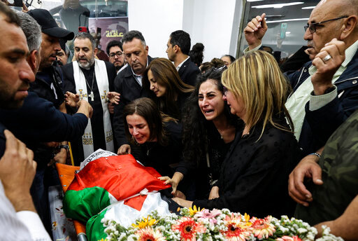 FILE - Colleagues and friends react as the Palestinian flag-draped body of veteran Al-Jazeera journalist Shireen Abu Akleh is brought to the news channel's office in the West Bank city of Ramallah, May 11, 2022. Israel's decision to absolve itself of responsibility for the shooting death of Abu Akleh drew criticism from international media on Thursday, Sept. 8, 2022, marking a further deterioration of relations between the military and reporters covering the conflict. The military said that neither the soldier nor commanders would face any punishment. (Abbas Momani/Pool via AP, File)