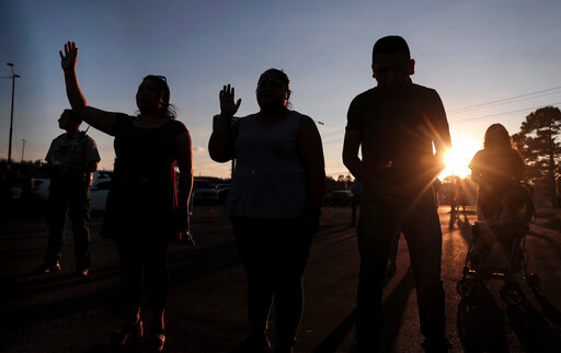 Mourners pray in the parking lot of an AutoZone, which was one of several crime scenes left in the wake of a shooting spree Thursday, Sept. 8, 2022 in Memphis, Tenn. Police say a gunman terrorized Memphis for hours as he cruised the streets shooting people, apparently at random. Four people were killed and three others were wounded.. (Patrick Lantrip/Daily Memphian via AP)