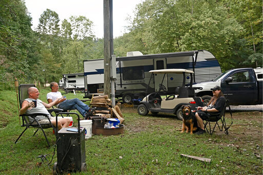 Lyndon Hall, top left, and Jordan Perkins, right, sit around their campsite at Jenny Wiley State Park in Prestonsburg, Ky., Tuesday, Sept. 6, 2022. Displaced by the floods in early July, the men have been staying in travel trailers as they wait for workers to become available to rebuild their homes. (AP Photo/Timothy D. Easley)