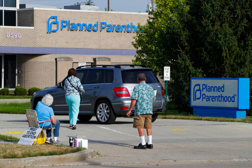 FILE - Abortion protesters attempt to hand out literature as they stand in the driveway of a Planned Parenthood clinic in Indianapolis, Aug. 16, 2019. Hospitals and abortion clinics in Indiana are preparing for the state's abortion ban to go into effect on Sept. 15, 2022. Starting Sept. 15, abortions will be permitted only in cases of rape and incest, before 10-weeks post-fertilization; to protect the life and physical health of the patient; and if a fetus is diagnosed with a lethal anomaly. The law also prohibits abortion clinics from providing any abortion care. (AP Photo/Michael Conroy, File)