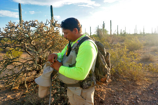 &Oacute;scar Andrade prays early, Sunday, Sept. 4, 2022 in the Ironwood Forest National Monument near Marana, Ariz., before searching for a missing Honduran migrant. The pastor heads a group, Capellanes del Desierto (Desert Chaplains), that provides recovery efforts for families of missing migrants. Andrade has received over 400 calls from families in Mexico and Central America whose relatives, sick, injured or exhausted, were left behind by smugglers in the borderlands. (AP Photo/Giovanna Dell'Orto)