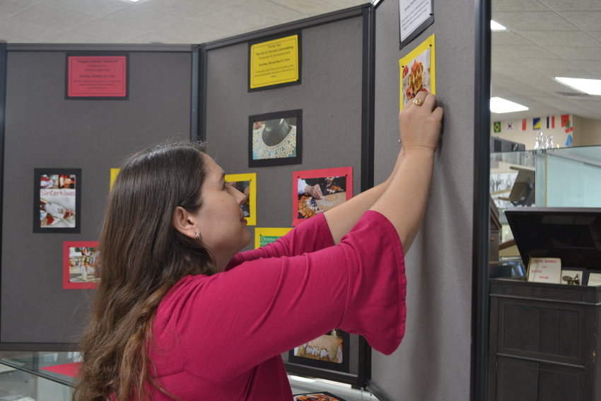 Miners Hall Museum Office Clerk Susan Bestor hangs pictures for the new quarterly exhibit, &ldquo;Belgian Heritage in SE Kansas,&rdquo; that is set to be ready for viewing on Saturday, Oct. 1.