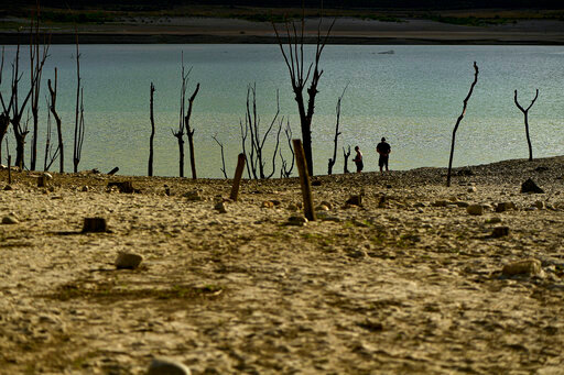FILE - People walk close to the border at Yesa's reservoir affected by drought, on a sunny summer day in Yesa, around 55 kilometers (34,17 miles), from Pamplona, northern Spain, Sept. 14, 2022. Widespread drought that dried up large parts of Europe, the United States and China this past summer was made 20 times more likely by climate change, according to a new study. (AP Photo/Alvaro Barrientos)