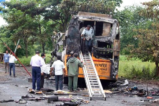 People inspect a bus that caught fire in a highway in Nashik, in the western Indian state of Maharashtra, Saturday, Oct. 8, 2022. The bus caught fire after hitting a truck on a highway in western India early Saturday, killing at least 12 passengers, said police officer Bhagwan Adke. Another 43 people with serious burns were taken to a hospital in Nashik. (AP Photo/Yatish Bhanu)