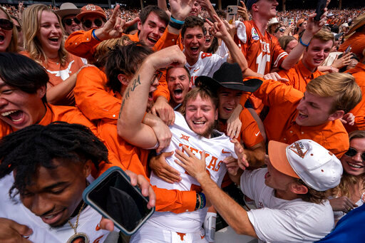 Texas quarterback Quinn Ewers (3) celebrates with fans after his team's 49-0 win over Oklahoma in an NCAA college football game at the Cotton Bowl, Saturday, Oct. 8, 2022, in Dallas. (AP Photo/Jeffrey McWhorter)