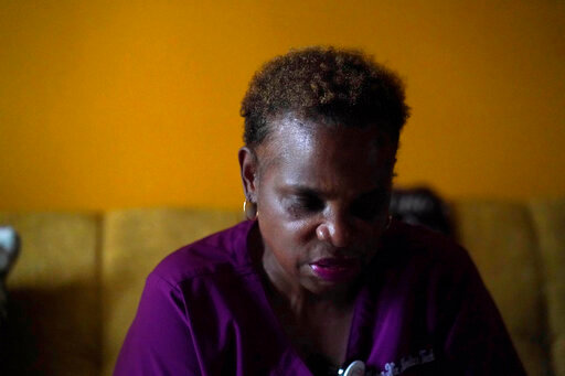 Karen Nix sits in her home before leaving for her evening work shift in New Orleans, Tuesday, Aug. 23, 2022. Nix tells her story of surviving hurricanes Katrina and Ida while living with cerebral palsy. (AP Photo/Gerald Herbert)
