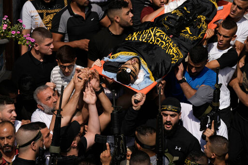 ADDS ISLAMIC JIHAD FLAG DESCRIPTION - Mourners carry the body of Matin Dababa, draped in the flag of the Islamic Jihad militant group, at his funeral in the Jenin refugee camp, Friday, Oct. 14, 2022. The Palestinian Health Ministry says the Israeli military shot and killed two Palestinians, including Dababa, during a raid into the Jenin refugee camp in the occupied West Bank. (AP Photo/ Majdi Mohammed)