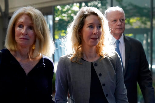 FILE - Former Theranos CEO Elizabeth Holmes, center, her mother, Noel Holmes, left, and father, Christian Holmes IV, arrive at federal court in San Jose, Calif., on Sept. 1, 2022. On Monday, Oct. 17, disgraced Theranos CEO Holmes will play one of her last cards to avoid a prison sentence when a federal judge questions a key prosecution witness who expressed post-trial regrets about testimony that helped convince a jury to convict her for investor fraud.(AP Photo/Jeff Chiu, File)