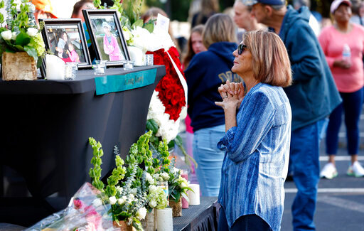 A woman stands before a photo of Raleigh shooting victim Susan Karnatz at a makeshift memorial at the Hedingham neighborhood. (Ethan Hyman/The News &amp; Observer via AP)