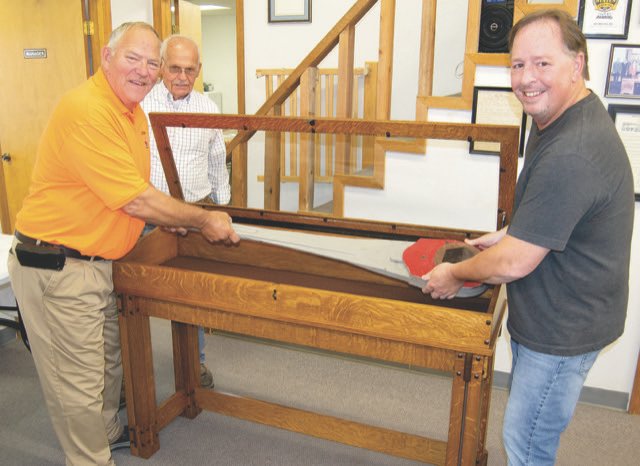 From left, Big Brutus Manager Joe Manns, Big Brutus Inc. Board Member Jim Lovell, and Evan Strum place a five-foot long, 67-pound ratchet wrench &mdash; which Evans borrowed without permission for several years &mdash; in a special cabinet that Evans recently built and donated to Big Brutus.