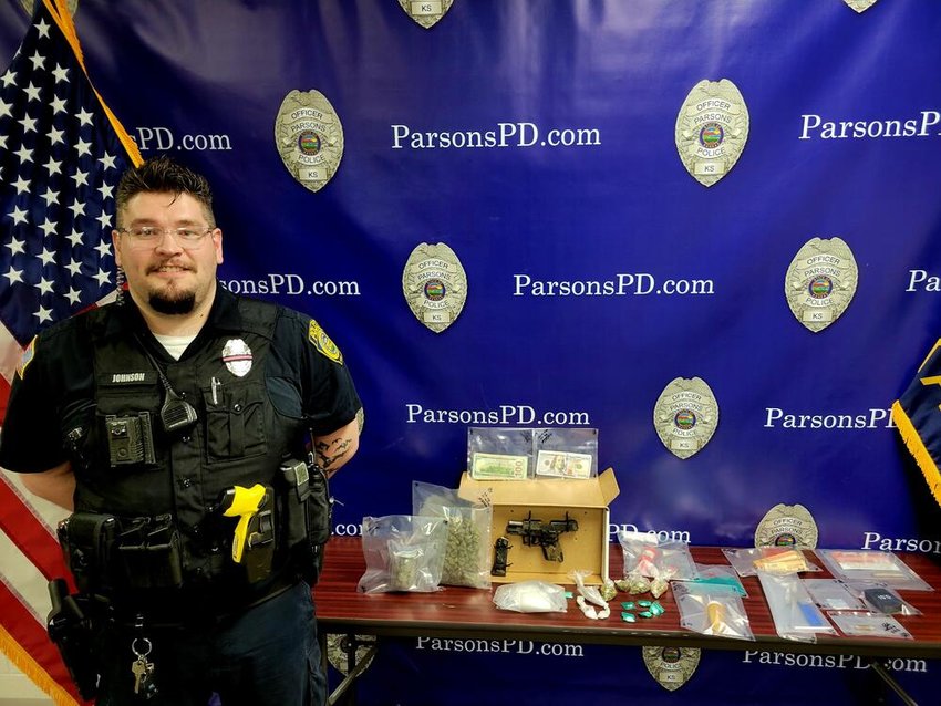 Parsons Police Officer Rory Johnson is pictured with a firearm, counterfeit $100 bills, several varieties of drugs and other evidence seized following a traffic stop earlier this week.