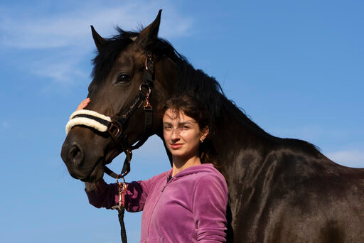 Viktoria Skliar poses for a photo Monday Aug. 8, 2022 with the horse 'Canada' at the stables called &quot;Magnat&quot; in the Kyiv region. In the last, brief conversations Skliar had with Oleksii Kisilishin, her detained boyfriend, the Ukrainian prisoner of war was making tentative plans for life after his release in an upcoming exchange with Russia. The next time Skliar saw Kisilishin, he was dead &mdash; one of several bodies in a photo of people local authorities said were killed when blasts ripped through a prison in a part of Ukraine's Donetsk region controlled by Moscow-backed separatists. (AP Photo/Vasilisa Stepanenko)