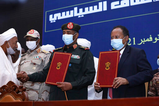 FILE - In this photo provided by the Sudan Transitional Sovereign Council, Sudan's top general Abdel Fattah Al-Burhan, center, and Prime Minister Abdalla Hamdok hold documents attended by Gen. Mohammed Hamdan Dagalo, second left, during a ceremony to reinstate Hamdok, who was deposed in a coup last month, in Khartoum, Sudan, Nov. 21, 2021. A year after a military takeover upended Sudan&rsquo;s transition to democracy on Oct. 25, 2021, growing divisions between the two powerful branches of the armed forces are further endangering Sudan&rsquo;s future. (Sudan Transitional Sovereign Council via AP, File)