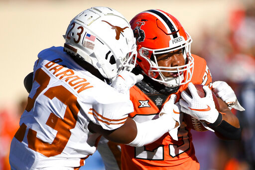 Texas defensive back Jahdae Barron, left, wraps up Oklahoma State running back Jaden Nixon, right, during the first half of an NCAA college football game Saturday, Oct. 22, 2022, in Stillwater, Okla. (AP Photo/Brody Schmidt)