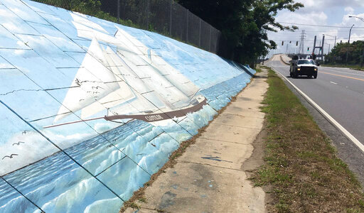 FILE - Traffic passes a mural of the slave ship Clotilda along Africatown Boulevard, in Mobile, Ala., May 30, 2019. Republican Tommy Tuberville told people Saturday, Oct. 8, 2022, at an election rally in Nevada that Democrats support reparations for the descendants of enslaved people because &ldquo;they think the people that do the crime are owed that.&rdquo; His remarks cut deeply for some, especially in and around Africatown, a community in Mobile, Alabama, that was founded by descendants of Africans smuggled in 1860 to the United States aboard a schooner called the Clotilda. (AP Photo/Kevin McGill, File)