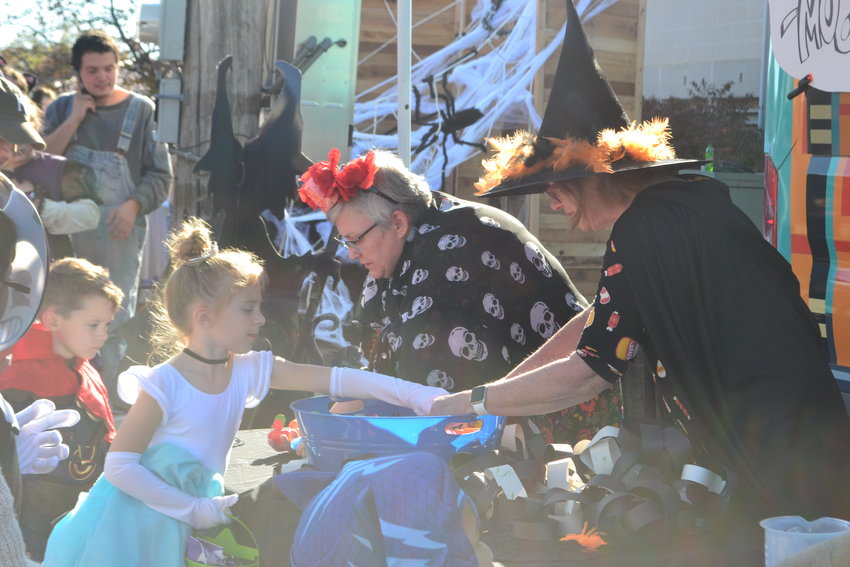 Pittsburg Public Library Director Bev Clarkson, right, and Gail Sheppard hand out rubber ducks and little toys to children at the Graveyard Get-Down on Halloween in the alley between the library and City Hall.