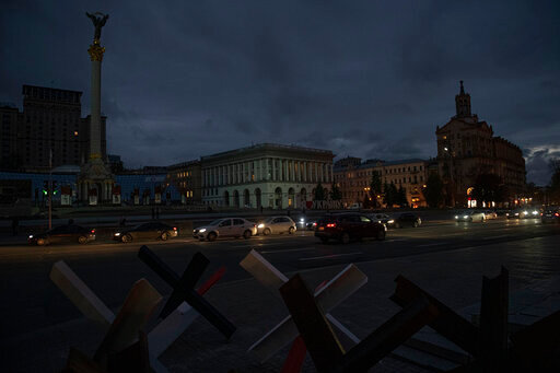 Cars pass in Independence Square at twilight in Kyiv, Ukraine, Monday, Oct. 31, 2022. Rolling blackouts are increasing across Ukraine as the government rushes to stabilise the energy grid and repair the system ahead of winter. (AP Photo/Andrew Kravchenko)