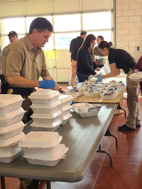 Pittsburg Deputy Police Chief Ben Henderson boxes up meals including a burger, bag of chips, a cookie, and a bottle of water for the annual Badges and Burgers fundraiser on Friday.