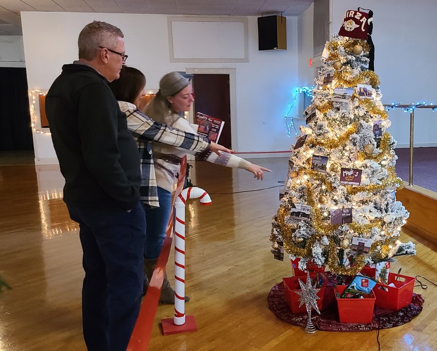 From left, Trey Coleman, Katie Swezey, and Frances Oldweiler point out the numerous gift cards covering one of the trees during the Pittsburg Area Chamber of Commerce&rsquo;s sneak peak of the Mirza Shrine&rsquo;s 3rd Annual Feztival of Trees, which will begin this Saturday.