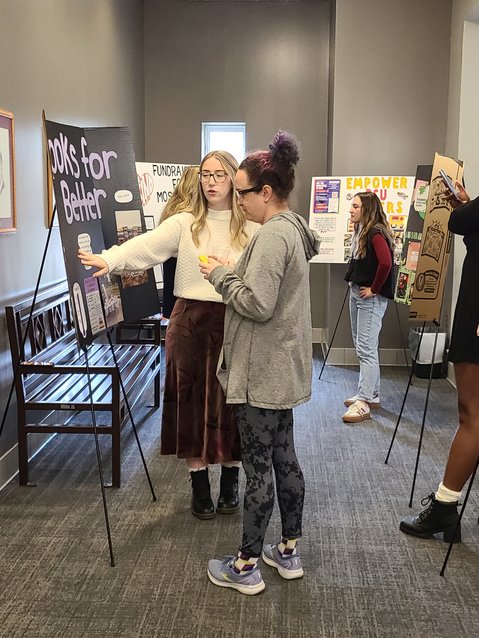 PSU social work student Carley Braschler, left, discusses her project &ldquo;Books for Better&rdquo; with Mona Jurshak at the PSU Social Work Program Community Project Showcase on Wednesday afternoon. Braschler was able to collect 230 books to distribute to Lakeside Elementary and local free little library boxes.