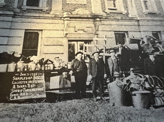 Crawford County Sheriff John Turkington, third from left, and other officials often displayed confiscated stills and moonshine in front of the jail in Girard; January 1925.