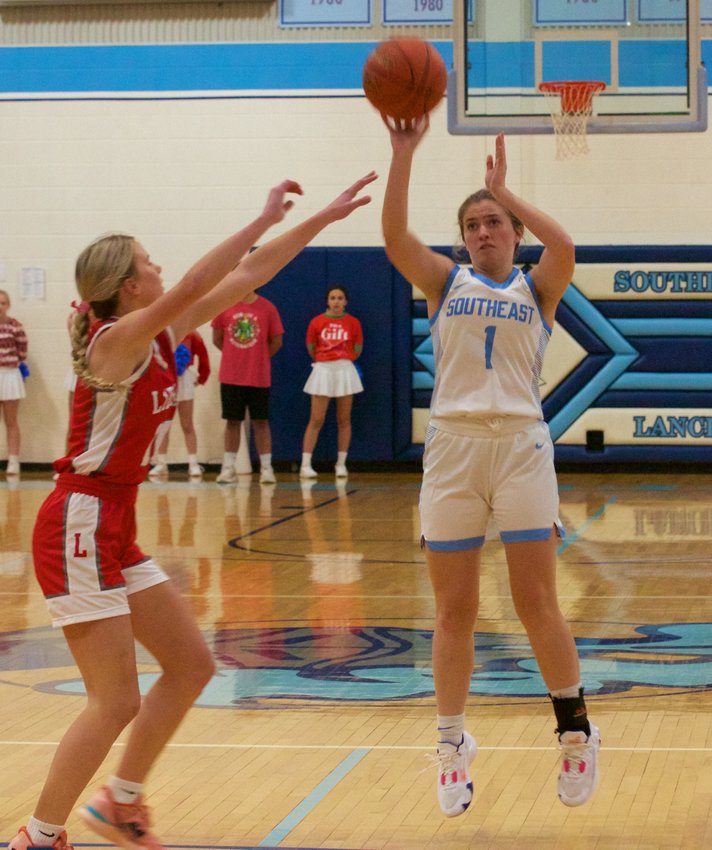 Southeast senior Audrey Jacobs delivers a shot from deep while Liberal junior Bailey Couch contests the attempt during the Lancers home opener against the Bulldogs on Tuesday.