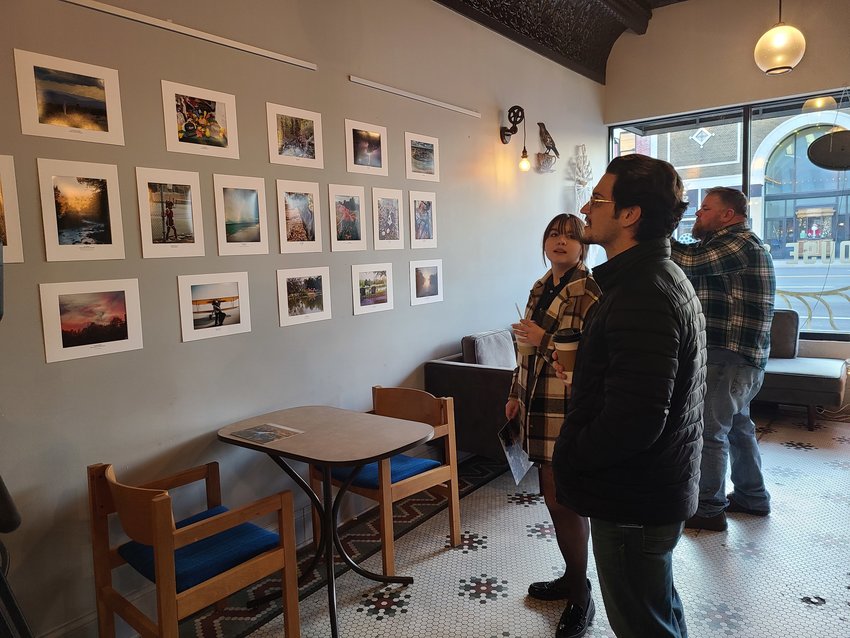 From left, Bri Green, Cody Renfro, and Troy Graham check out the photo display at the reception for city employees at Root Coffeehouse on Thursday afternoon.