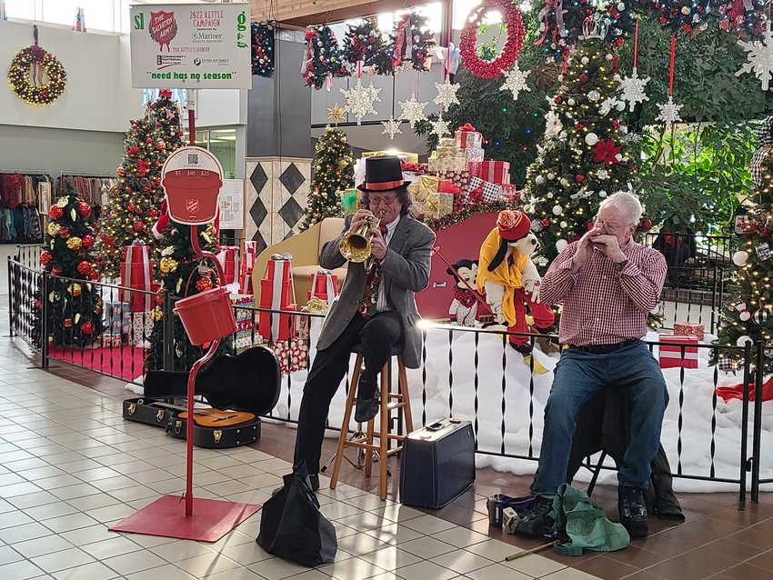 Jim Harris, left, plays the flugelhorn while Denis Kavanagh plays the harmonica for the Salvation Army&rsquo;s Red Kettle Campaign at the Meadowbrook Mall on Wednesday afternoon.