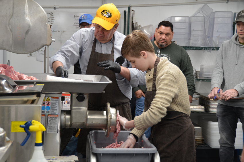 Ben Probert, left, and Hadrian Zurek work together to grind the meat during Matt DeMoss&rsquo;s sausage making class at The Meat Shed on Saturday.