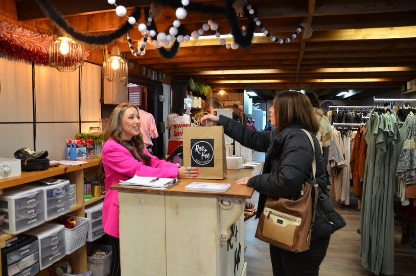 Owner of the newly rebranded Rae and Kae Boutique Shelby Cannon gives customer Katie Painter her purchase at the store&rsquo;s ribbon cutting event last week.