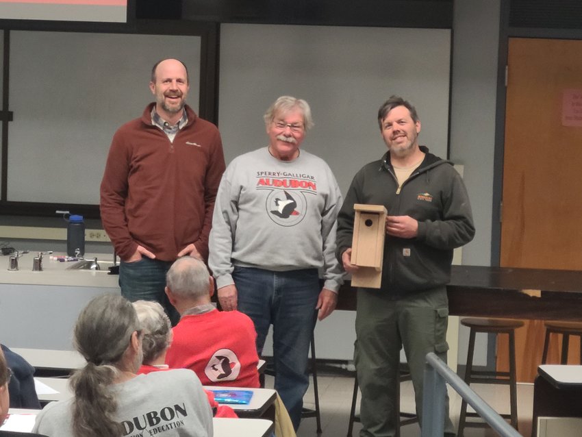 From left, Pittsburg State University associate professor of Biology Andrew George and Steve Ford present Natural Resource Ecologist and Prairie State Park Manager Andrew Braun with a birdhouse at the Sperry-Galligar Audubon Society&rsquo;s monthly meeting.