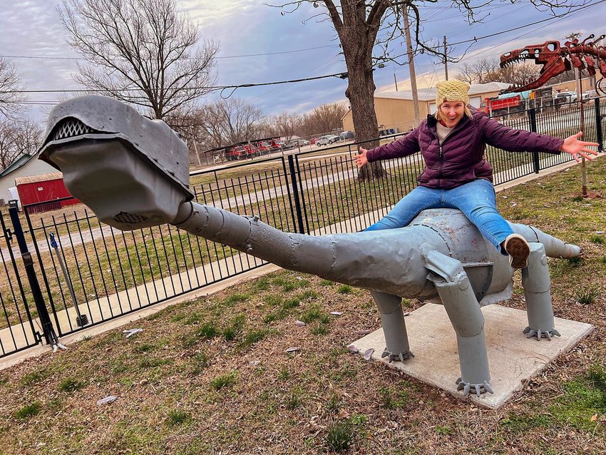 Travel blogger and Omaha native Kim Reiner rides one of the dinosaurs in Erie as she and her family make their way through southeast Kansas this week.&nbsp;