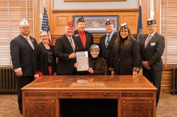 Governor Kelly holds the signed proclamation with Kansas American Legion delegates. &nbsp;